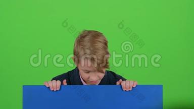 小男孩从一张<strong>蓝色海报</strong>后面出现，看着他再次躲藏起来。 绿色屏幕
